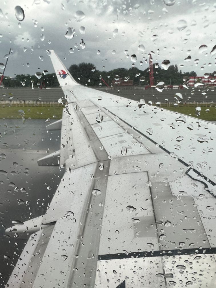An aeroplane wing with droplets of water on the window's surface.